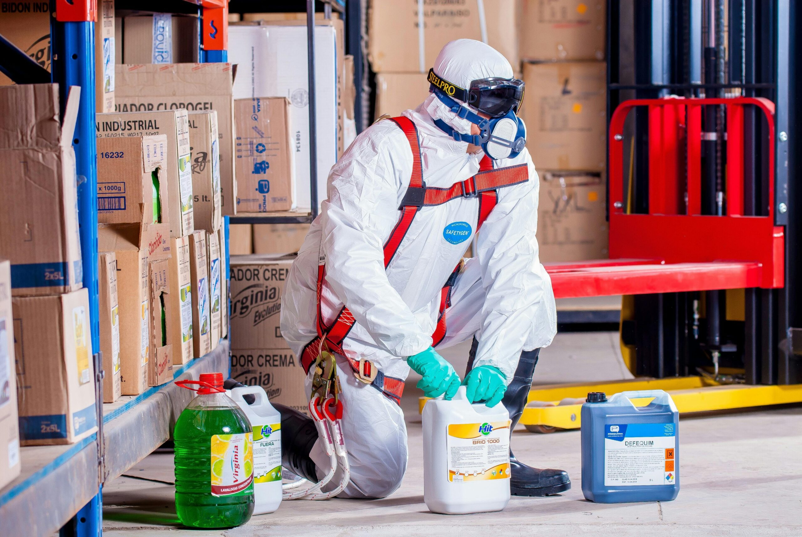 Industrial worker in protective gear handling chemicals in a warehouse environment.