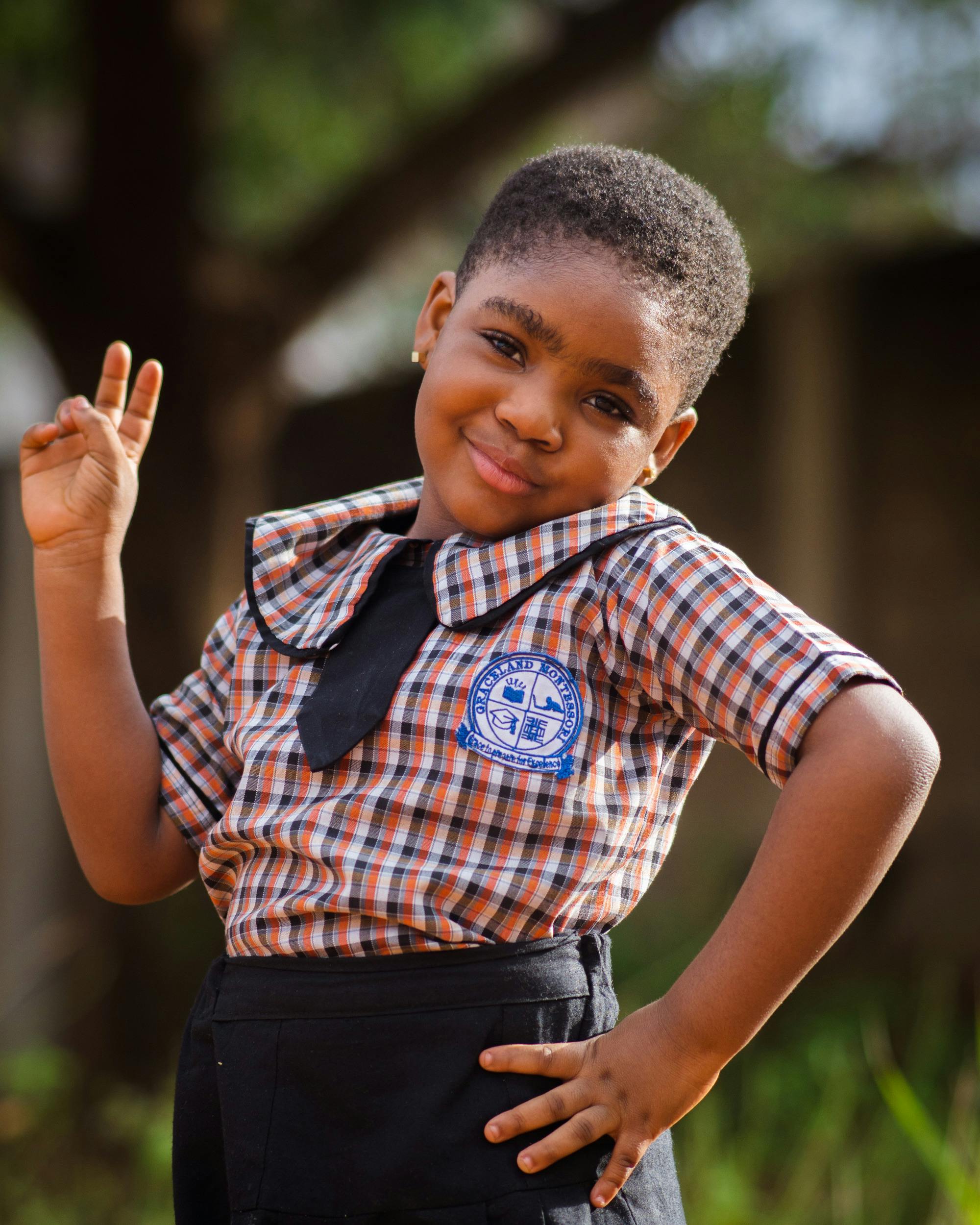 Charming young girl in school uniform confidently posing outdoors, expressing joy and pride.
