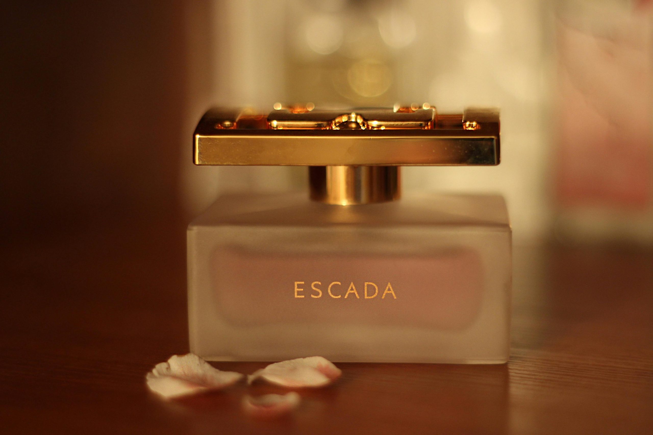 Close-up of a luxury perfume bottle with petals on a wooden table.