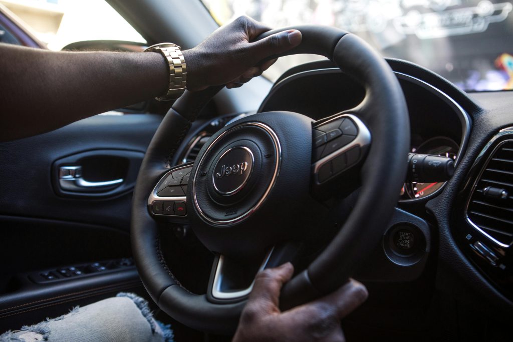 Close-up of a man's hands on a luxury car steering wheel highlighting modern interior.